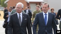 Malaysian Prime Minister Najib Razak, left, walks along the tarmac with Australian Prime Minister Tony Abbott on their way to meet crew members involved in search of wreckage and debris of the missing Malaysia Airlines MH370 in Perth, Australia, Thursday,