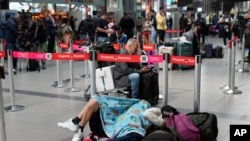 Pasajeros de Viva Air duermen junto a sus maletas luego de que la aerolínea de bajo costo suspendiera sus operaciones en el Aeropuerto Internacional El Dorado de Bogotá, el 28 de febrero de 2023. 