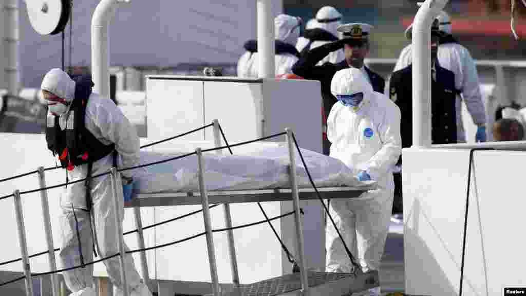 Des agents de la Garde côtière italienne, couverts de vêtements de protection, transportent le corps d'un immigrant mort, hors de leur navire Bruno Gregoretti, à Senglea, à La Valette Grand Harbor, le 20 avril 2015.
