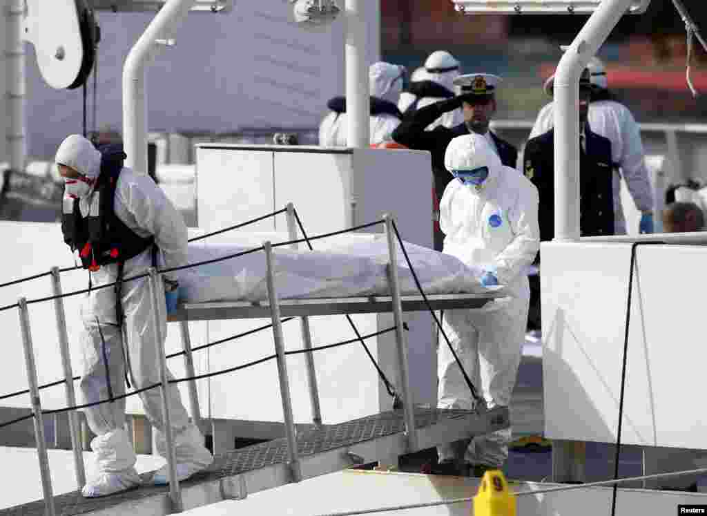 Italian Coast Guard personnel in protective clothing carry the body of a dead immigrant off their ship, Bruno Gregoretti, in Senglea, in Valletta's Grand Harbor, April 20, 2015.