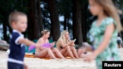 Russian tourists sit at the beach in Phuket, Thailand