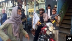 FILE - A Taliban fighter sits on his motorcycle adorned with a Taliban flag in a street in Kunduz, Afghanistan. 