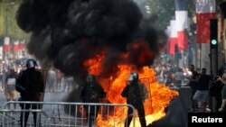 Une toilette mobile brûle lors d'affrontements entre forces de l'ordre et manifestants sur l'avenue des Champs-Élysées après le traditionnel défilé militaire du 14 juillet à Paris, en France, le 14 juillet 2019. REUTERS / Pascal Rossignol