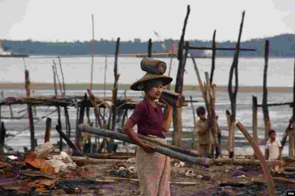 2012年11月,在被焚毁的若开邦穆斯林社区皎漂(Kyauk Phyu),一位妇女搬着捡来的废木。 (D. Schearf/VOA)