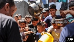 Anak-anak Palestina antre membawa panci untuk menerima bantuan makanan dari dapur di sekolah Abu Zeitun yang dikelola oleh Badan Bantuan dan Pekerjaan PBB untuk Pengungsi Palestina (UNRWA) di kamp Jabalia, Jalur Gaza utara 13 Juni 2024 (foto: dok).