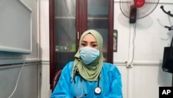 This May 13, 2020, picture provided by Dr. Marwa al-Khafaji shows the doctor back at work after 20 days in isolation after she tested positive for the coronavirus at a hospital in Karbala, Iraq.