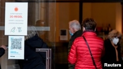 People pass by a sign spelling out COVID-19 rules at the entrance to the Dresden State Art Collections, in Dresden, Germany, Nov. 19, 2021.