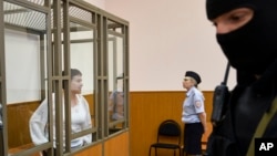 FILE - Jailed Ukrainian pilot Nadiya Savchenko (L) stands in a defendant's cage during a court hearing in the town of Donetsk, Rostov-on-Don region, Russia, Sept. 29, 2015.
