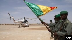 Des soldats maliens devant l'hélicoptère transportant le Premier ministre malien atterrit à Menaka, au Mali, le 9 mai 2018.
