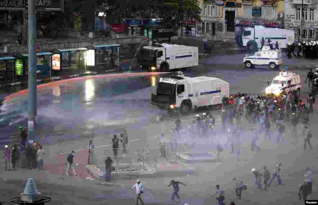 People run as riot police fire a water cannon on Gezi Park protesters, Istanbul, June 15, 2013.