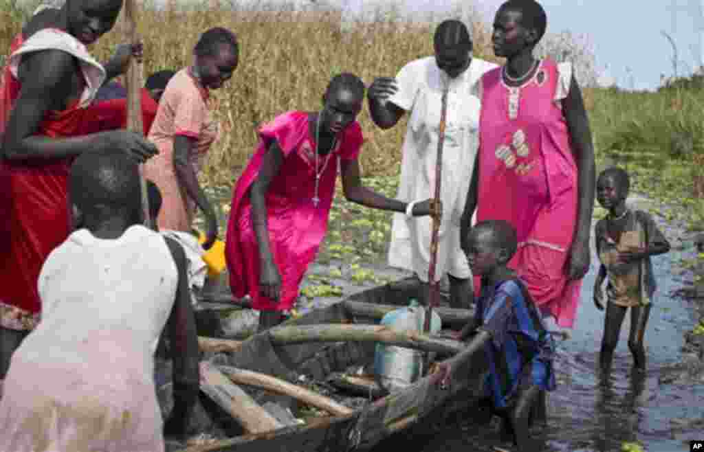 Une famille de l’ethnie Nuer à la recherche des mécadiments et de la nourriture, mais qui doit regagner leur village dans la zone contrôlée par des rebelles, prépare d’embarquer dans un canoë pour traverser une zone inondée où elle sera contrainte de marcher dans le marécage près de la Mission Onusienne au Sud Soudan (UNMISS) au village de Bentiu, au Sud Soudan.