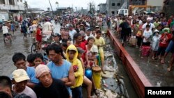 Para penyintas topan Haiyan mengantre beras gratis di sebuah gudang milik pengusaha di kota Tacloban, Filipina tengah (12/11). (Reuters/Erik De Castro)