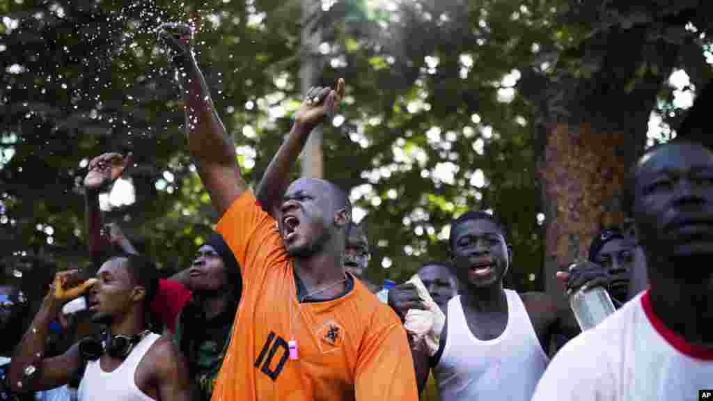 Sur cette photo prise le jeudi 30 octobre 2014, les manifestants vocifèrent alors qu’ils viennent de saccager et brûler un bâtiment du Parlement au Burkina Faso. Des scènes de liesse et des pillages ont eu lieu au Burkina Faso après que le président Blaise Compaoré a annoncé vendredi 31 octobre 2014 qu’il quittait le pouvoir. Il a régné 27 années. (AP Photo / Theo Renaut)