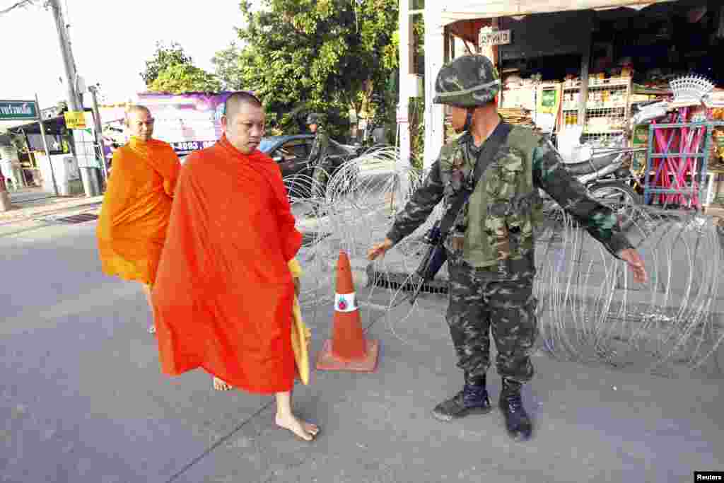 Barefoot Buddhist monks walk past a checkpoint near a pro-government "red shirt" supporter encampment in Nakhon Pathom province, on the outskirts of Bangkok, May 22, 2014.