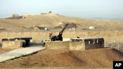 Seorang petugas keamanan berdiri di samping senjata anti-pesawat saat dia memindai di sekitar fasilitas pengayaan nuklir Iran di Natanz, 300 km selatan ibu kota Teheran, Iran, Senin, 9 April 2007. (Foto: AP)