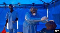 Un membre de l'équipe de réponse rapide du ministère de la santé prélève un échantillon sur un homme qui a récemment été en contact avec un cas confirmé de coronavirus à Juba, au Soudan du Sud, le 13 avril 2020. (AFP)