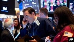Trader Gregory Rowe, center, and others work on the floor of the New York Stock Exchange, March 16, 2020. (AP Photo/Craig Ruttle)
