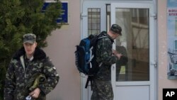 Oficiales de la fuerza aérea ucraniana caminan con sus maletas en la base aérea de Belbek, en las afueras de Sebastopol, Crimea, el 20 de marzo de 2014.