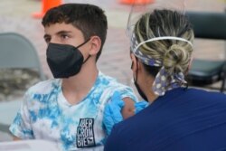 FILE - A boy, 12, meeting the age requirement to get vaccinated against COVID-19, gets his first dose of the Pfizer vaccine, in Miami, Florida, Aug. 9, 2021.