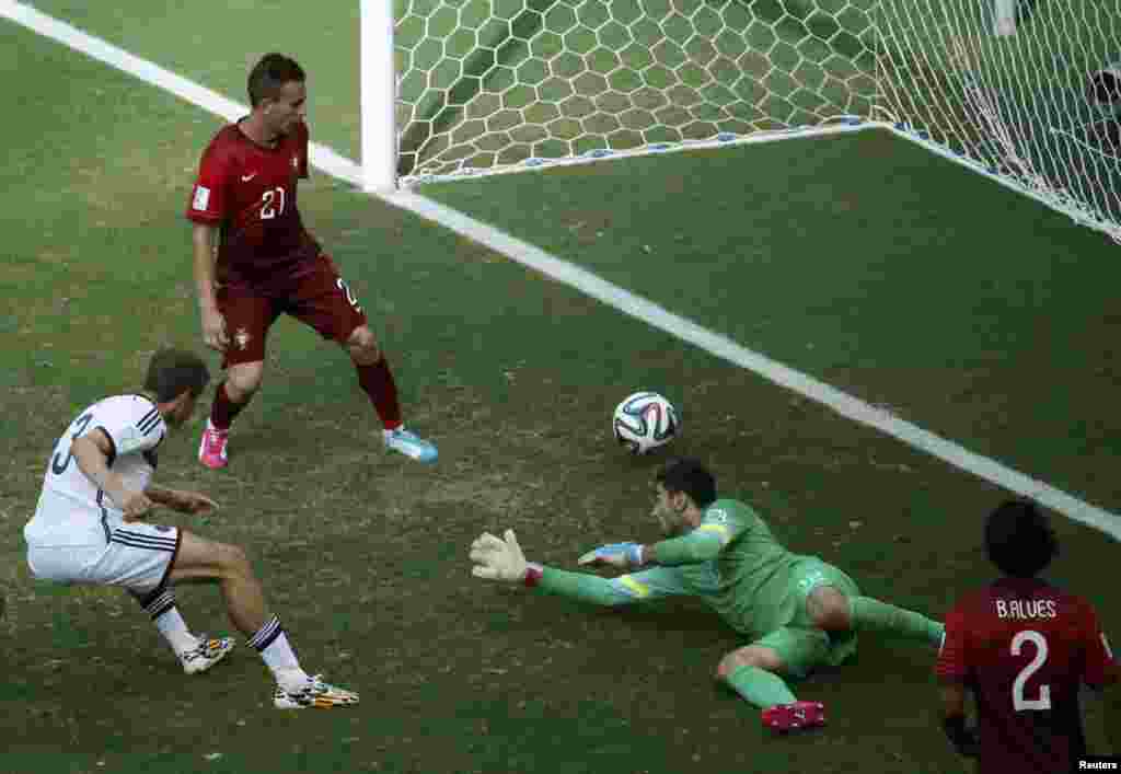 Germany's Thomas Mueller (L) shoots to score against Portugal for his hat-trick during their 2014 World Cup Group G soccer match at the Fonte Nova arena in Salvador, June 16, 2014. 