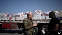 Isroil armiyasi polkovnigi Moshe Tetro speaks G'azoga kirishi kerak bo'lgan gumanitar yordam mashinalari yonida jurnalist bilan gaplashmoqda, Kerem Shalom, 10-yanvar, 2024 
