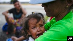 Emily Lucena sentada con su hija Alessandra Lugo mientras hacen autostop a Colombia desde Barinas, Venezuela, el viernes 7 de enero de 2022. Lucerna dice que está migrando a Colombia para buscar un tratamiento asequible para la hipercalcemia de su hija. 
