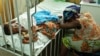 FILE - Hassana Ousmane rHassana Ousmane rests her head against the bed where 21-month-old Zeinab, suffering from diarrhea, rests, Princess Marie Louise Children's Hospital, Accra, April 25, 2012.