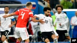 Pesepak bola Rusia, Sergei Ignashevich (kiri), dan Mohamed Salah dari Mesir (kanan) berebut menguasai bola dalam laga penyisihan Grup A antara Rusia dan Mesir di Piala Dunia 2018 di Stadion St. Petersburg, Rusia, 19 Juni 2018.