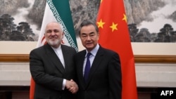 Menteri Luar Negeri China Wang Yi (kanan) berjabat tangan dengan Menteri Luar Negeri Iran Mohammad Javad Zarif dalam perempuan di Beijing, China, 31 Desember 2019. (Foto: AFP)