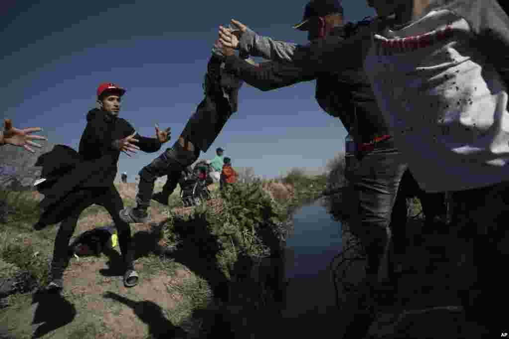 Los inmigrantes pasan a un niño a las alturas del Ro Grande en Ciudad Járez, México el 29 de marzo de 2023. Las imágenes retratan las vicisitudes de los inmigrantes por alcanzar el territorio de EEUU. [Foto: Christian Chavez}