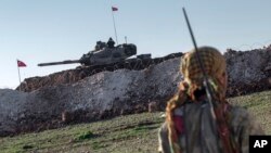 Anggota milisi Kurdi Suriah YPG berpatroli dekat tank militer Turki di Desa Esme, Provinsi Aleppo, Suriah, 22 Februari 2015.