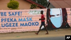 Un jeune garçon passe devant un mur avec des graffitis exhortant les gens à porter des masques à Harare, le 28 mai 2020.