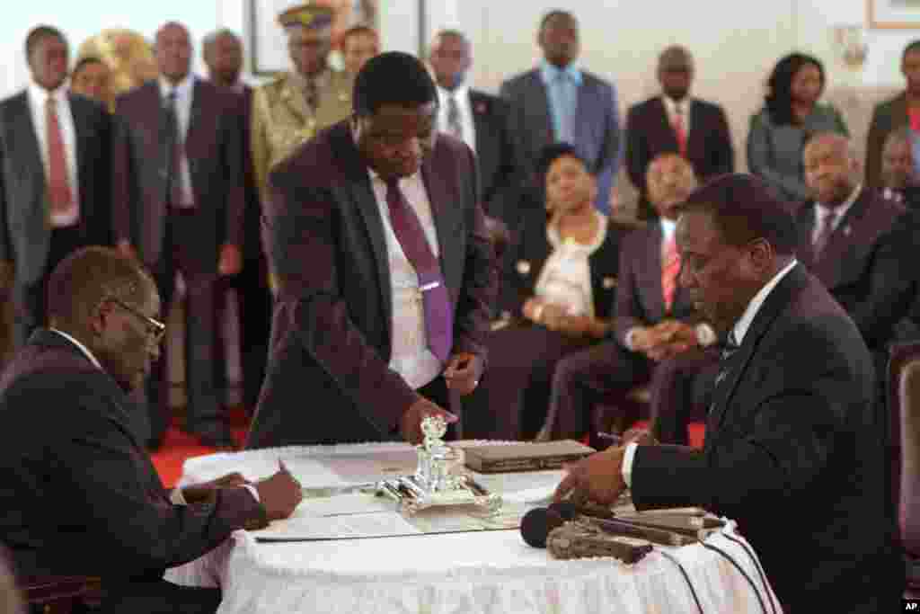 Emmerson Mnangagwa, à droite, signe des papiers au cours d'une cérémonie de prestation de serment pour son poste de vice-président devant le président zimbabwéen Robert Mugabe, à gauche, au State House à Harare, vendredi 12 décembre 2014