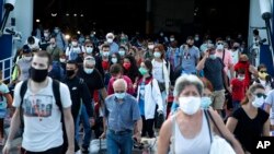 Des voyageurs portant des masques faciaux contre la propagation du nouveau coronavirus, débarquent d'un ferry au port du Pirée, près d'Athènes, le jeudi 20 août 2020. (Photo AP / Thanassis Stavrakis)
