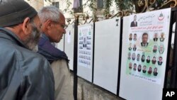 Des passants regardent les panneaux pour les législatives à Alger, Algérie, le 9 avril 2017. 
