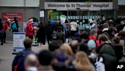 Orang-orang mengantri, di kanan, untuk suntikan booster virus corona di Rumah Sakit St Thomas, di London, 14 Desember 2021. (Foto: AP)