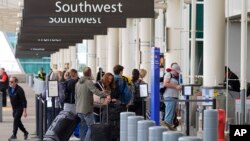 ARCHIVO: Los viajeros revisan sus equipajes en la acera de Southwest Airlines el martes 16 de abril de 2024, afuera del Aeropuerto Internacional de Denver, en Colorado. Southwest es la única de las seis grandes aerolíneas que no apoya la demanda del sector contra el gobierno.