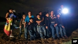 FILE - A group of young migrants from Honduras and El Salvador who crossed the U.S.-Mexico border illegally are stopped in Granjeno, Texas, June 25, 2014.