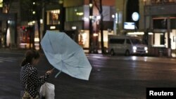 Seorang warga Tokyo di distrik perbelanjaan Ginza kesulitan membawa payungnya akibat tiupan angin kencang dampak topan Jelawat yang melanda Jepang (30/9).