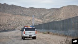 FILE - A U.S. Border Patrol agent drives near the U.S.-Mexico border fence in Sunland Park, New Mexico, Jan. 4, 2016.