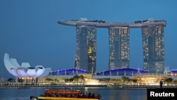 စင်ကာပူနိုင်ငံ Marina Bay Sands ဟိုတယ်အနီးမှ ဖြတ်သွားနေသည့် ကမ္ဘာလှည့်ခရီးသည်တင် လှေတစီး။ (ဇူလိုင် ၃၊ ၂၀၁၉)