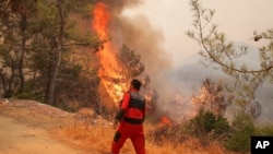 Firefighters work in the smoke-engulfed Mazi area as wildfires rolled down the hill toward the seashore, forcing people to be evacuated, in Bodrum, Mugla, Turkey, Aug. 1, 2021. 