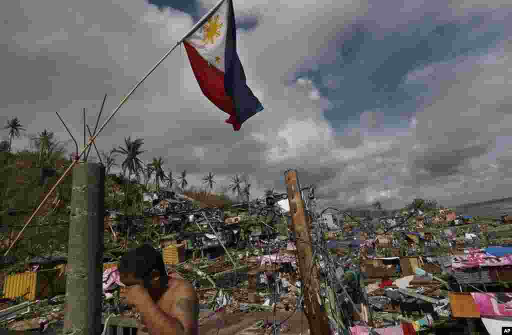 A survivor wipes his face under a Philippines national flag in Tacloban, central Philippines, Nov. 13, 2013.