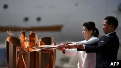 Peraih medali emas Olimpiade tiga kali Jepang Saori Yoshida (kiri) dan Tadahiro Nomura (kanan) menyalakan api Olimpiade Tokyo 2020 dengan obori Olimpiade yang dibawa dari Yunani, di Pangkalan Angkatan Udara Matsushima di Higashimatsushima, Jepang, 20 Maret 2020.