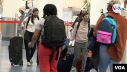 Pasajeros en el Aeropuerto Internacional de Miami caminan con mascarillas para tomar un vuelo para el día de Acción de Gracias. [Foto: Antoni Belchi, VOA]