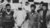 یکی از گروگان‌های سفارت آمریکا در تهران با چشم‌های بسته، به همراه چند تن از انقلابیون طرفدار خمینی - ۹ نوامبر ۱۹۷۹ 