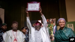 Rais-Mteule Bola Tinubu (katikati) akionyesha cheti chake, akiwa amefuatana na mkewe Oluremi Tinubu (kulia) pamoja na mwenyekiti wa Tume Huru ya Taifa ya Uchaguzi (INEC) Mahmood Yakubu (kushoto) huko Abuja, tarehe 1 Machi 2023. Picha na AP/Ben Curtis. 