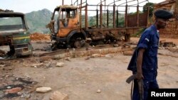 Un policier congolais passant devant les restes calcinés de véhicules au siège du mouvement politico-religieux Bundu Dia Kongo, à Matadi, Kongo central, le 19 mars 2008. 