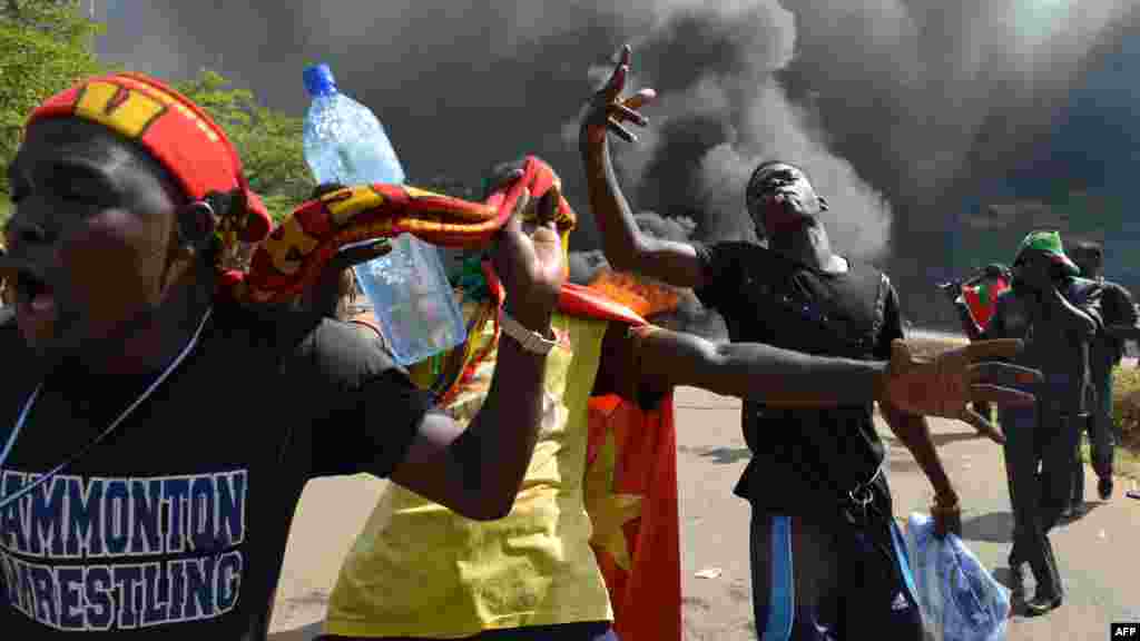 Les manifestants se tiennent devant le parlement où des voitures et des documents brulent, à Ouagadougou le 30 Octobre, 2014. Des centaines de manifestants en colère au Burkina Faso ont pris d'assaut le parlement le 30 Octobre avant d'y mettre le feu en signe de protestation contre l'intention de modifier la Constitution pour permettre au Président Blaise Compaoré pour étendre son règne de 27 ans. AFP PHOTO / ISSOUF SANOGO