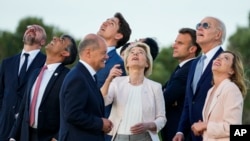 De derecha a izquierda, la primera ministra italiana, Giorgia Meloni, el presidente de EEUU, Joe Biden, observan junto a otros mandatarios del G7 una demostración de paracaidismo durante la cumbre de líderes en Borgo Egnazia, Italia, el 13 de junio de 2024.